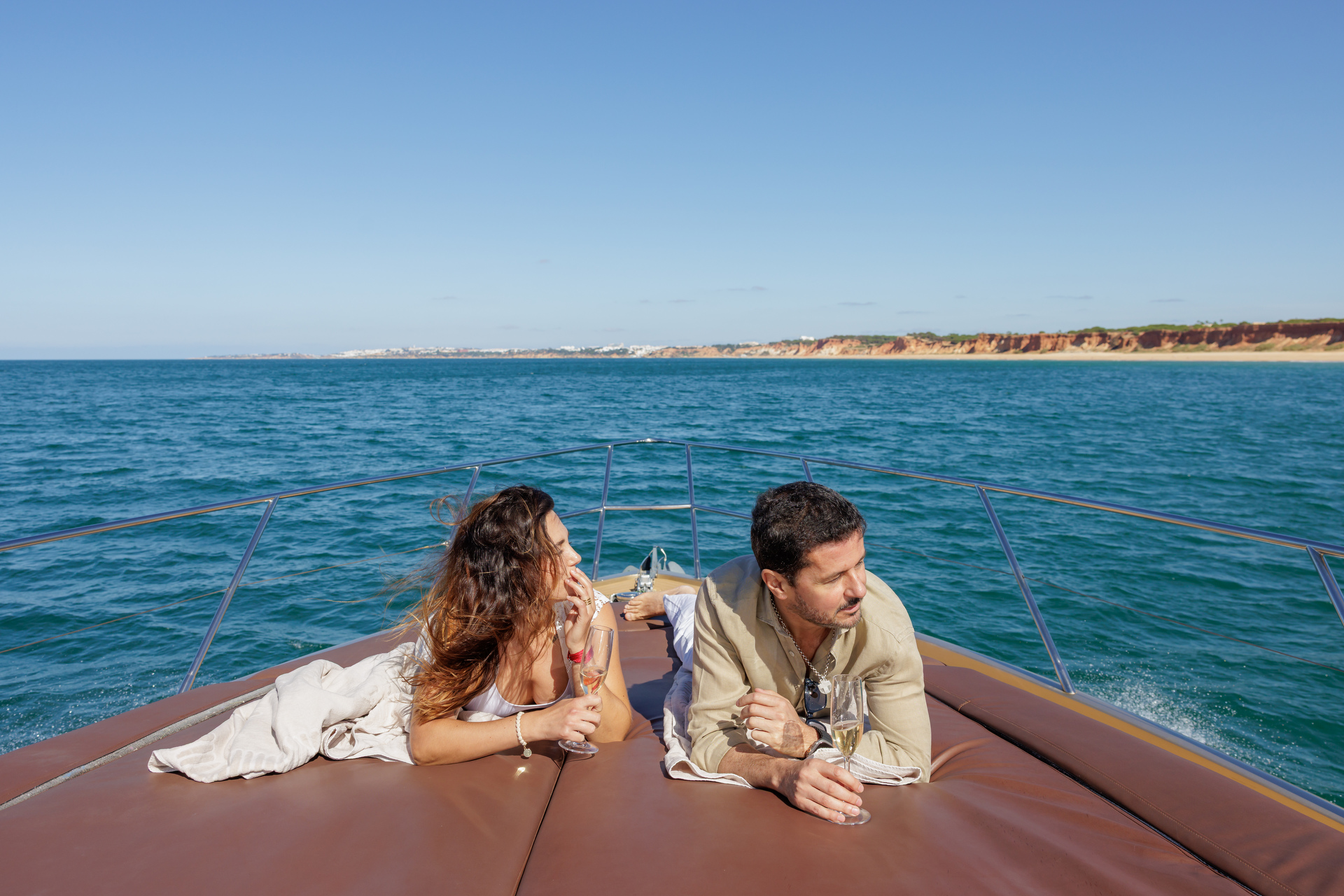 Couple lounging on the bow of the yacht with champagne and ocean views